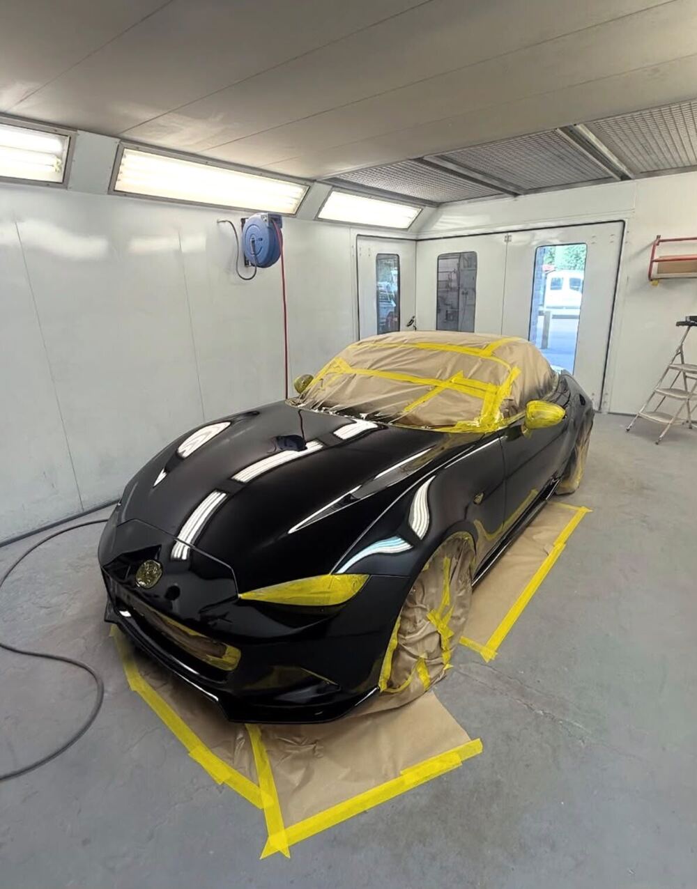 A black sports car freshly painted and masked up in the spray booth at Smith Motors